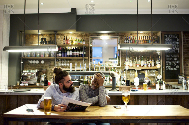 Couple looking over newspaper in a bar