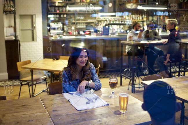 Woman with newspaper looking at friend in bar