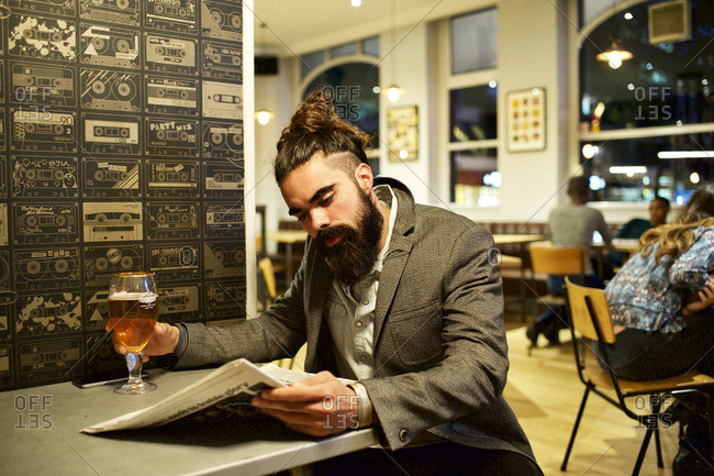 Man reading newspaper in solitude at a bar