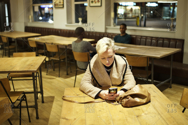 Woman alone at bar table checking her phone