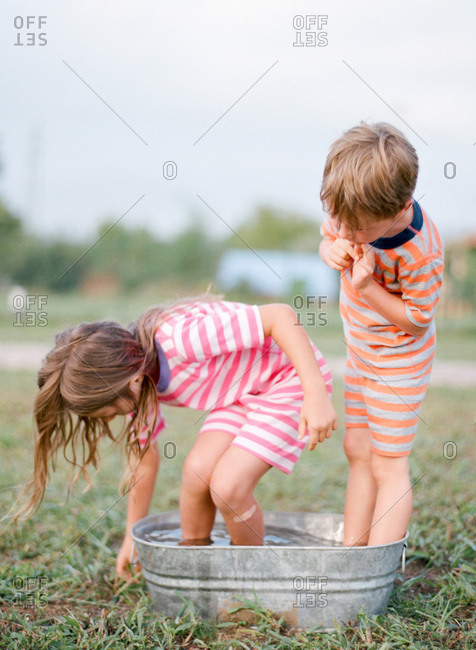 Brother and sister standing in a bucket of water