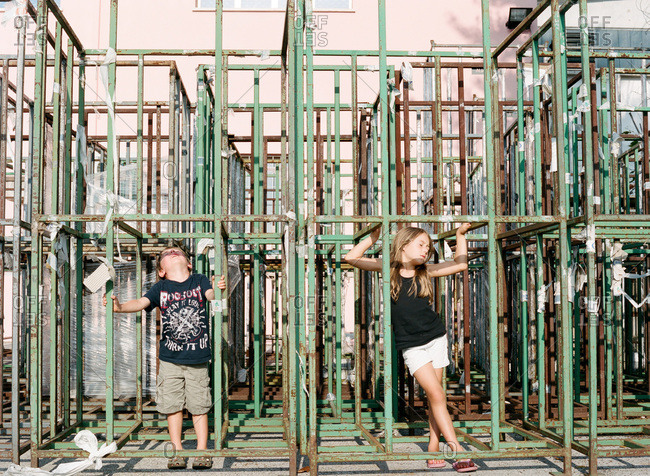 Kids standing in between rusty metal scaffolding bars