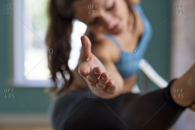 Dancer's arm rests on her leg as she stretches at the barre