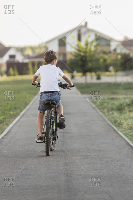 Rear view of boy cycling on footpath