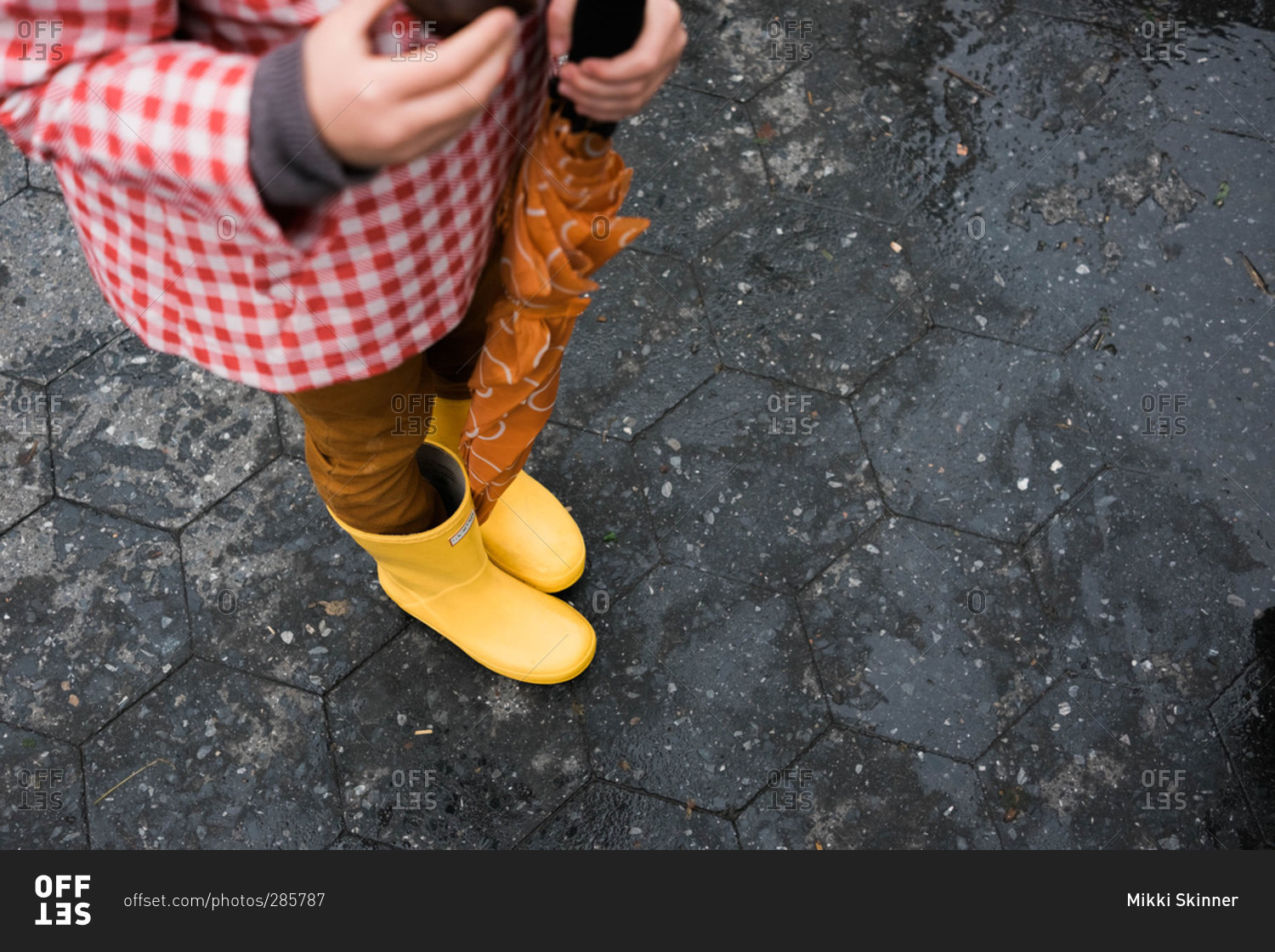 Girl with rain gear standing on pavement