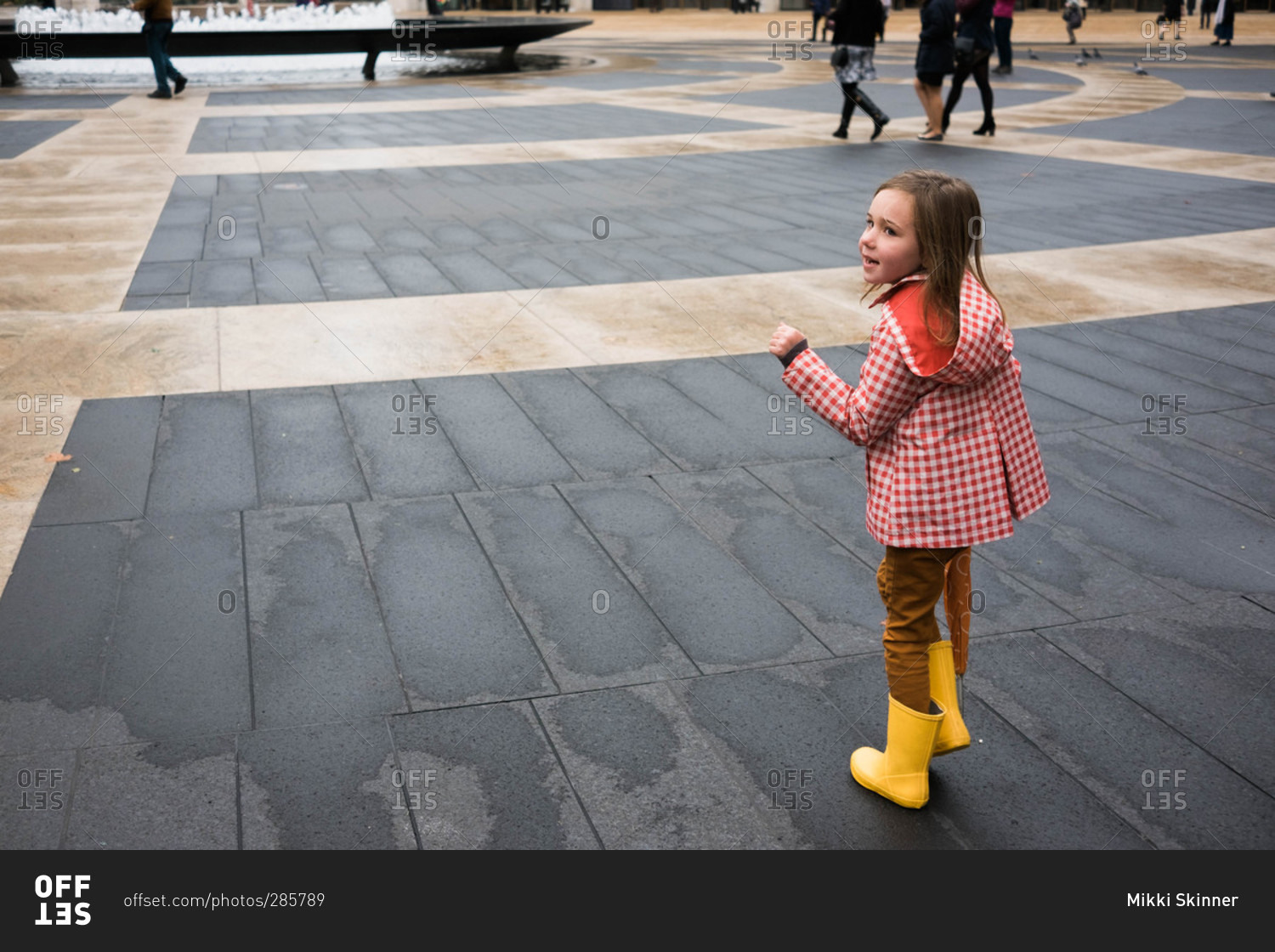 Girl in rain clothing standing in city square