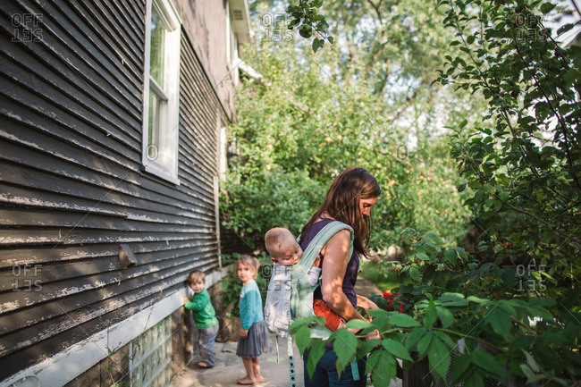 Mother Holding Baby In Back Pack Style Baby Carrier While Walking