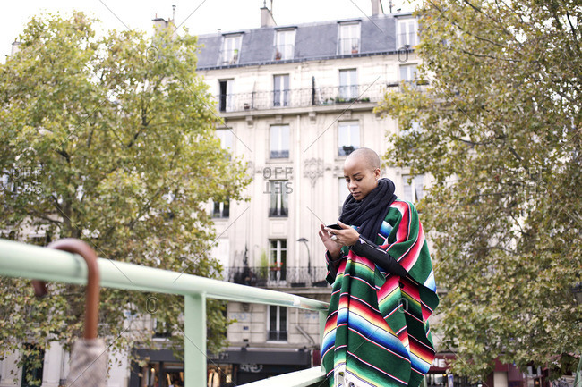 Woman in poncho with phone in Paris