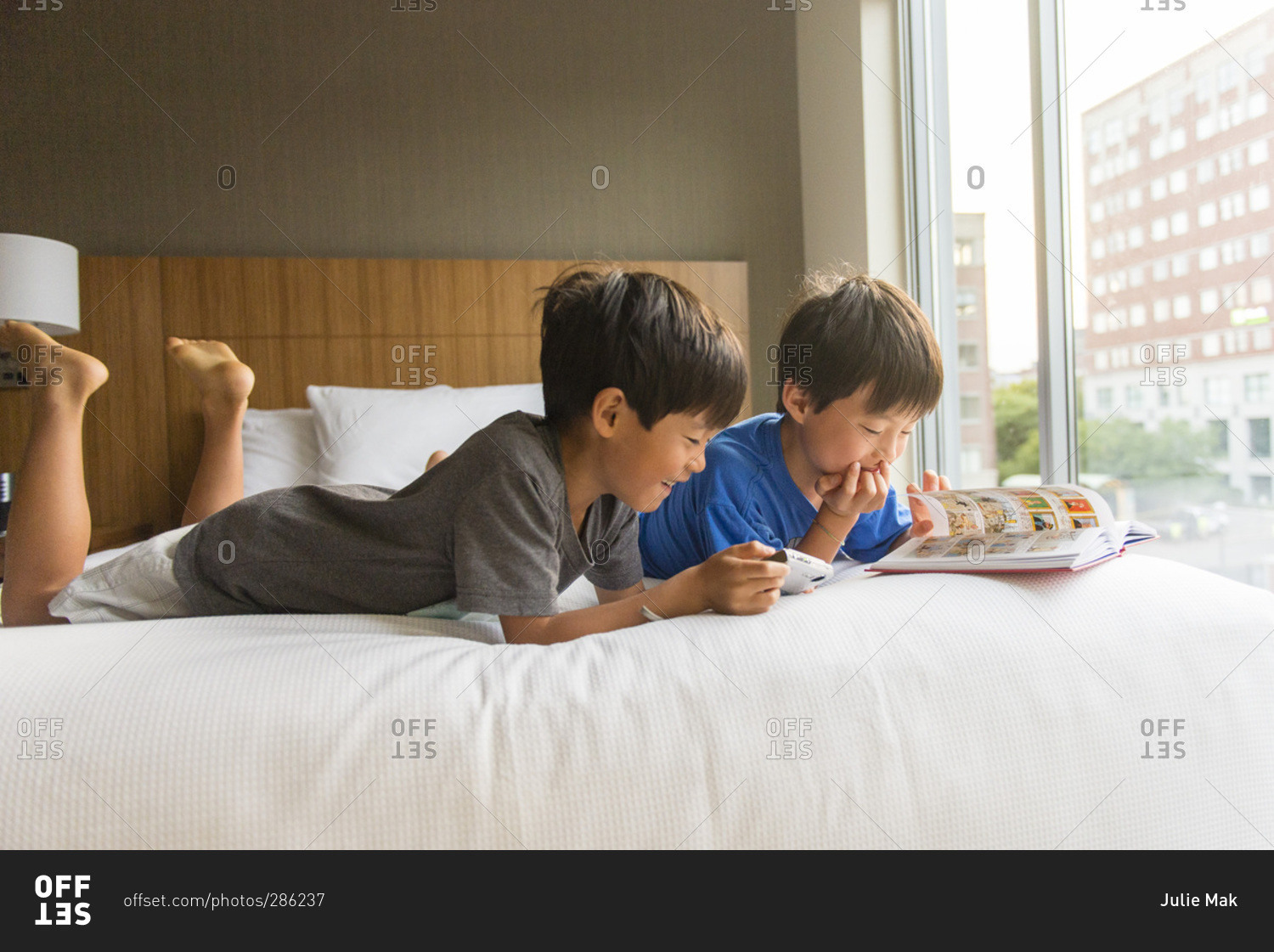 Young asian boys looking at comic book in hotel bed
