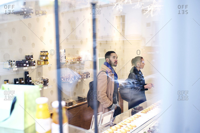 View of couple inside bakery buying treats through a window