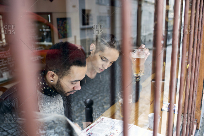 View through window of couple sitting inside a restaurant reading a newspaper