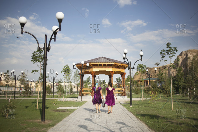 Two young women in purple dresses walking in a park in Uzbekistan