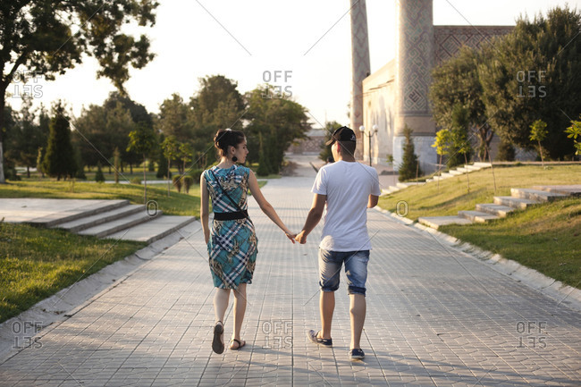 Samarcanda, Uzbekistan - June 28, 2015: Young couple hold hands walking in park
