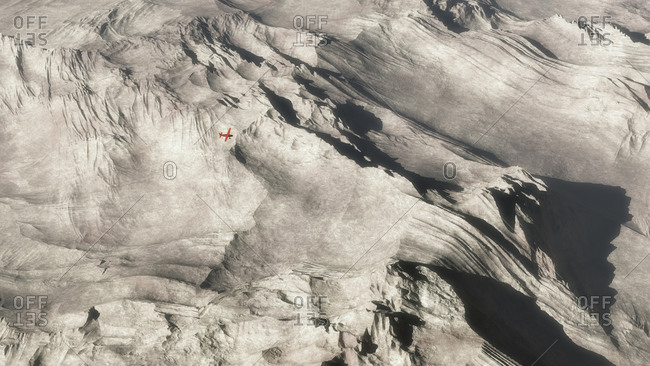 Aerial of small red  airplane over barren mountain landscape