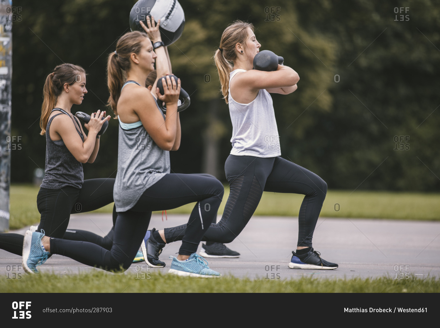 Four women doing lunges during an outdoor boot camp workout