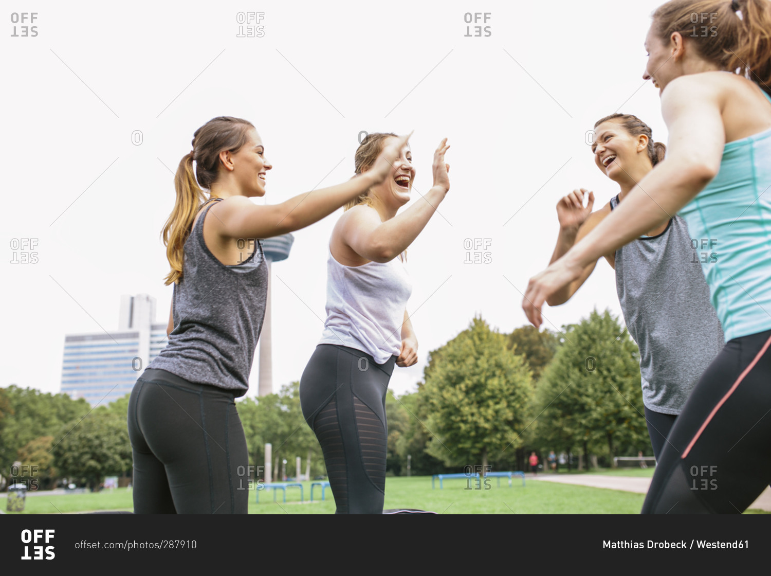 Four happy women high fiving after an outdoor workout