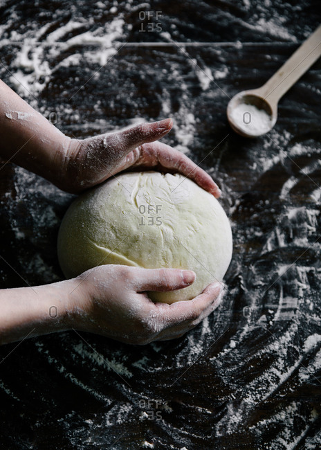Hands forming raw dough into ball