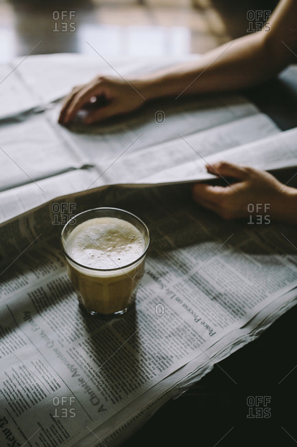 Woman reading newspaper with glass of coffee