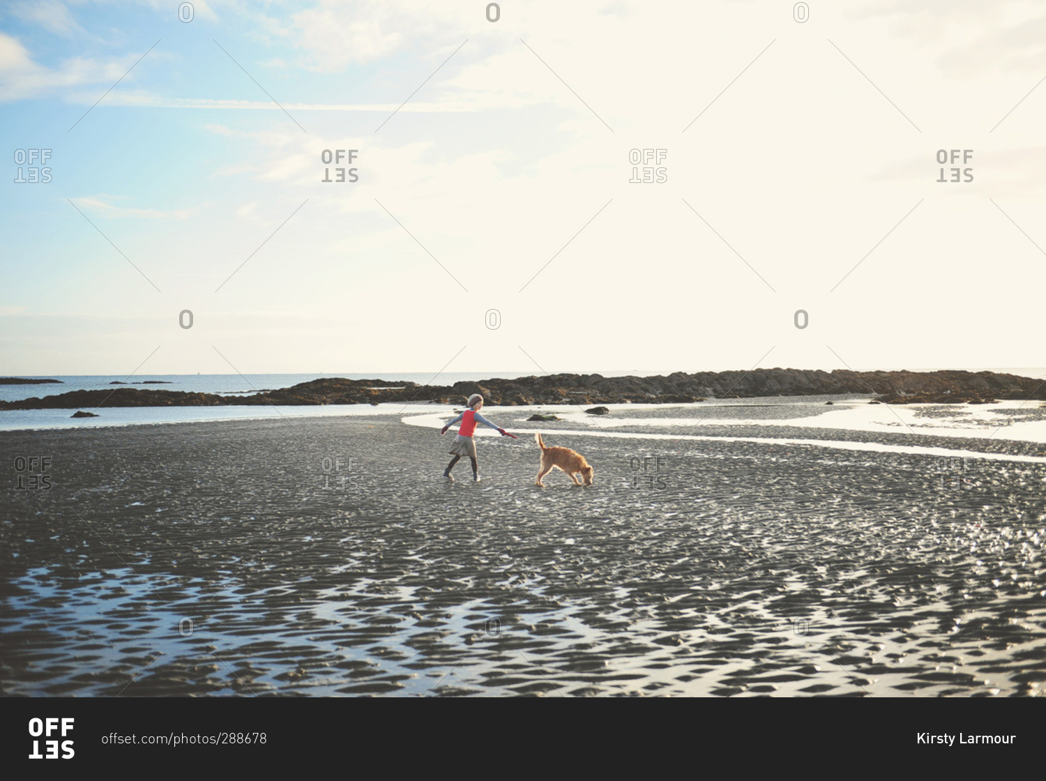 Girl walking dog on cold beach