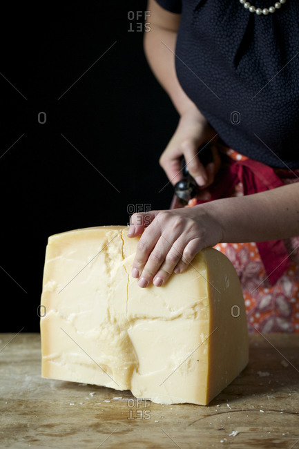 Closeup of a man slicing a Parmigiano Reggiano cheese wheel Stock