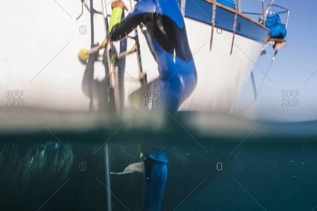 Boy climbing up boat ladder after swimming in Catalina, California