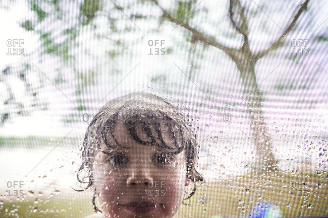 Wet boy looking into screen window