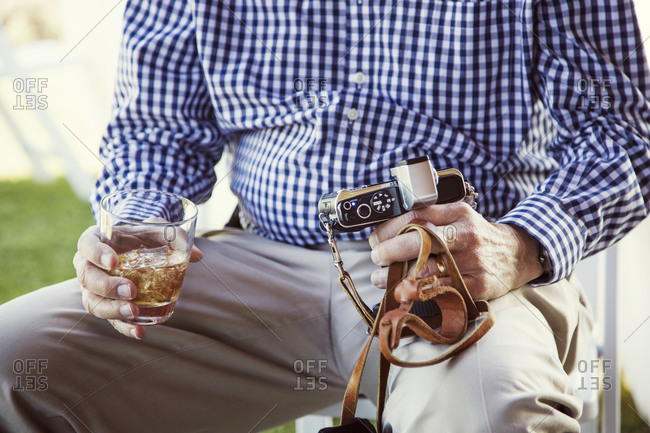 Lap of man holding drink and camera