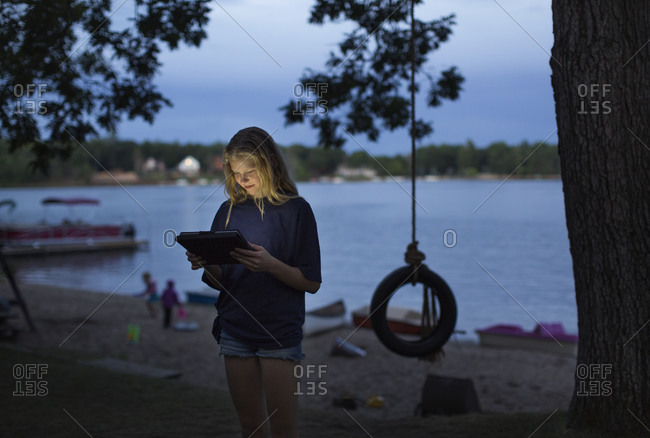 Girl on a lakeshore with a tablet