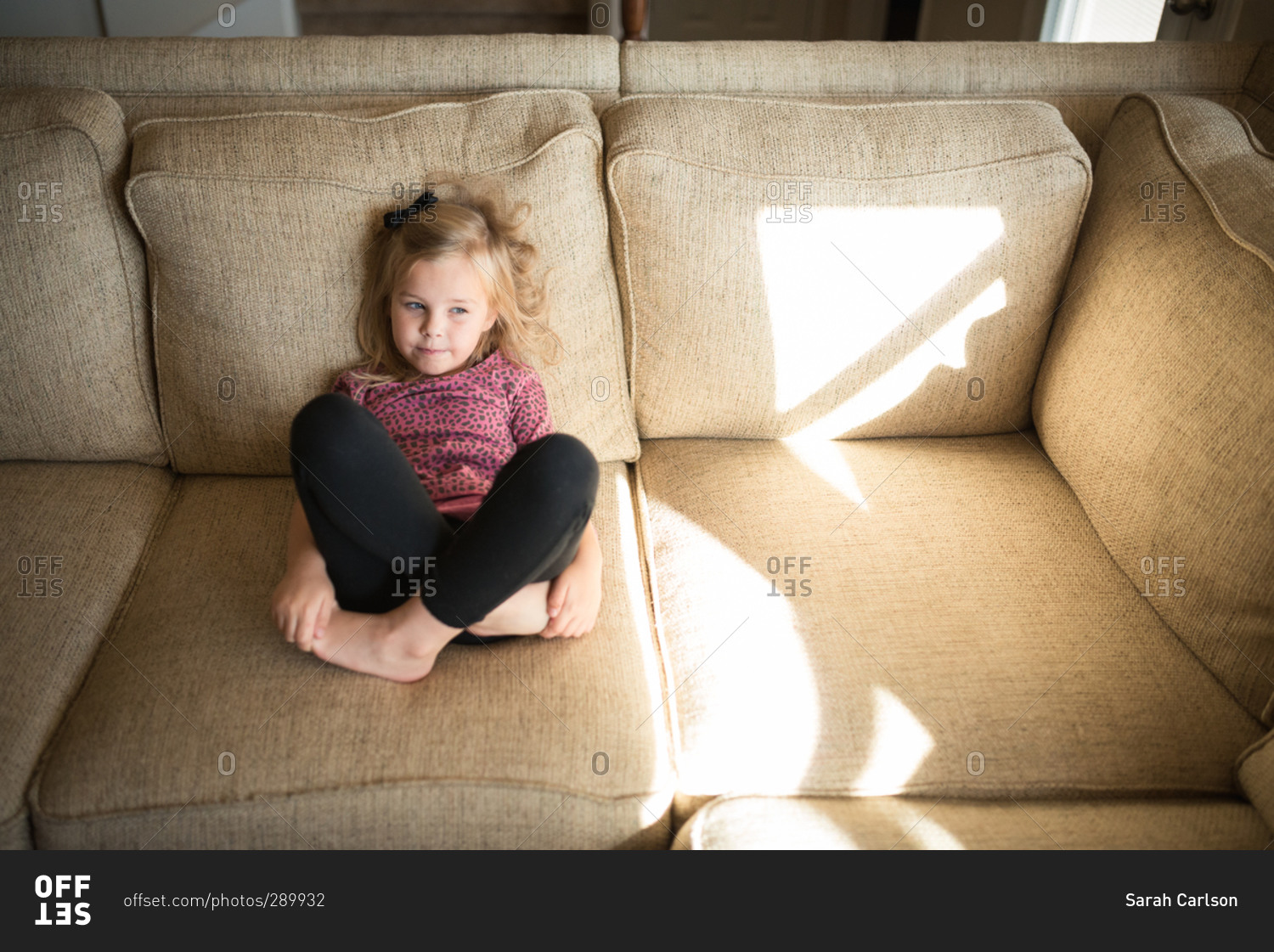 High angle view of a little girl sitting on a couch with her legs