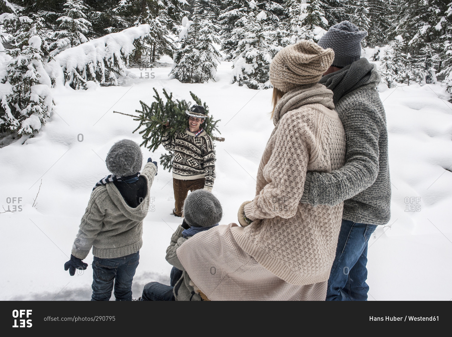 Man with Christmas tree and family together in winter forest
