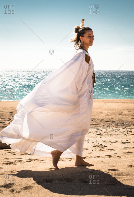 Woman in white robe walking on beach