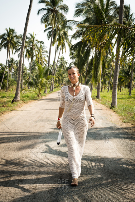 Woman in aboriginal makeup and knitted dress walking down road with feather