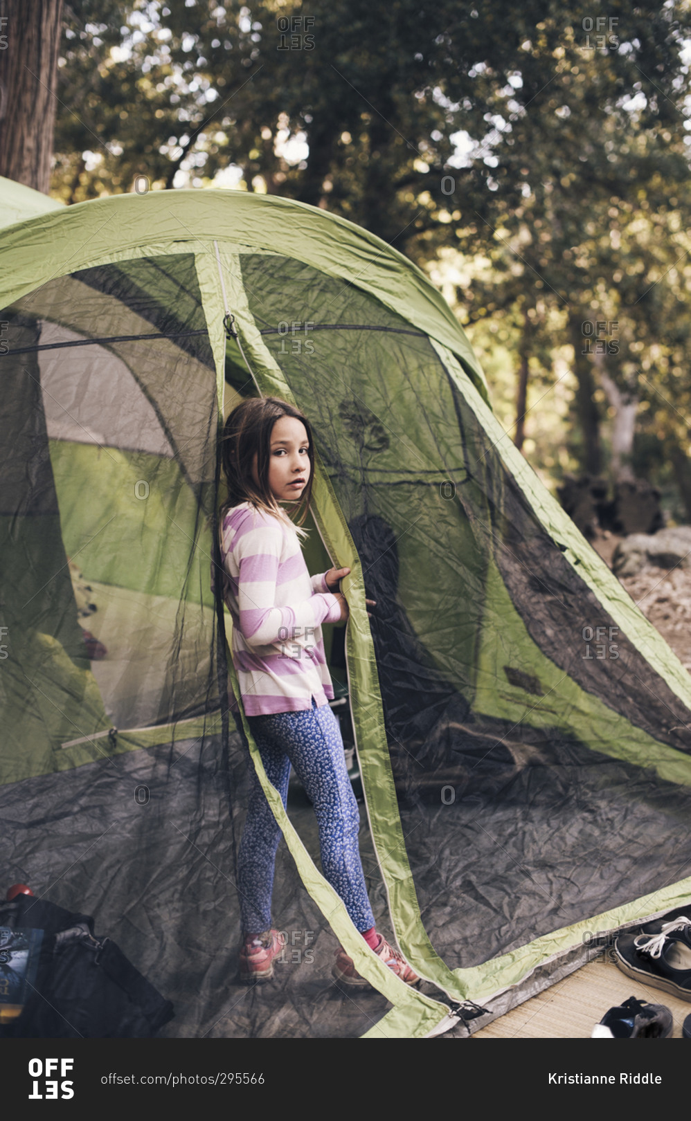 Little girl standing at the entrance of a camping tent