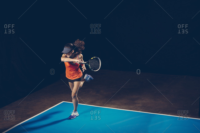 Brunette athletic woman on a blue tennis court