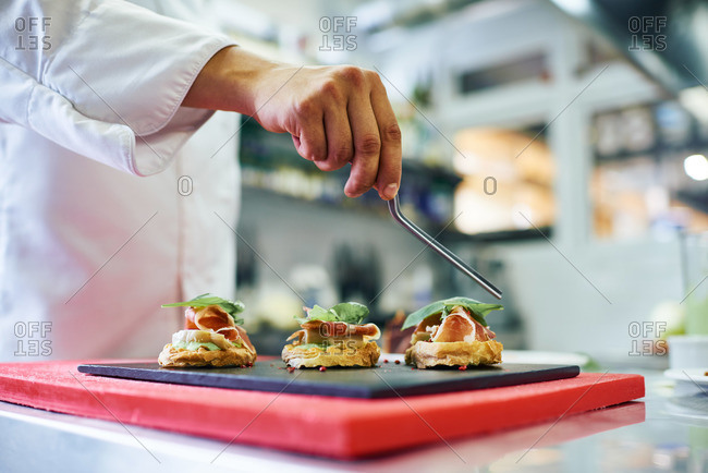 Chef placing basil on appetizers