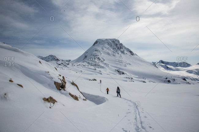 Skiers at the top of a pass with a wide expanse of the Coast Mountains ahead during the Spearhead Traverse in Whistler, British Columbia, Canada