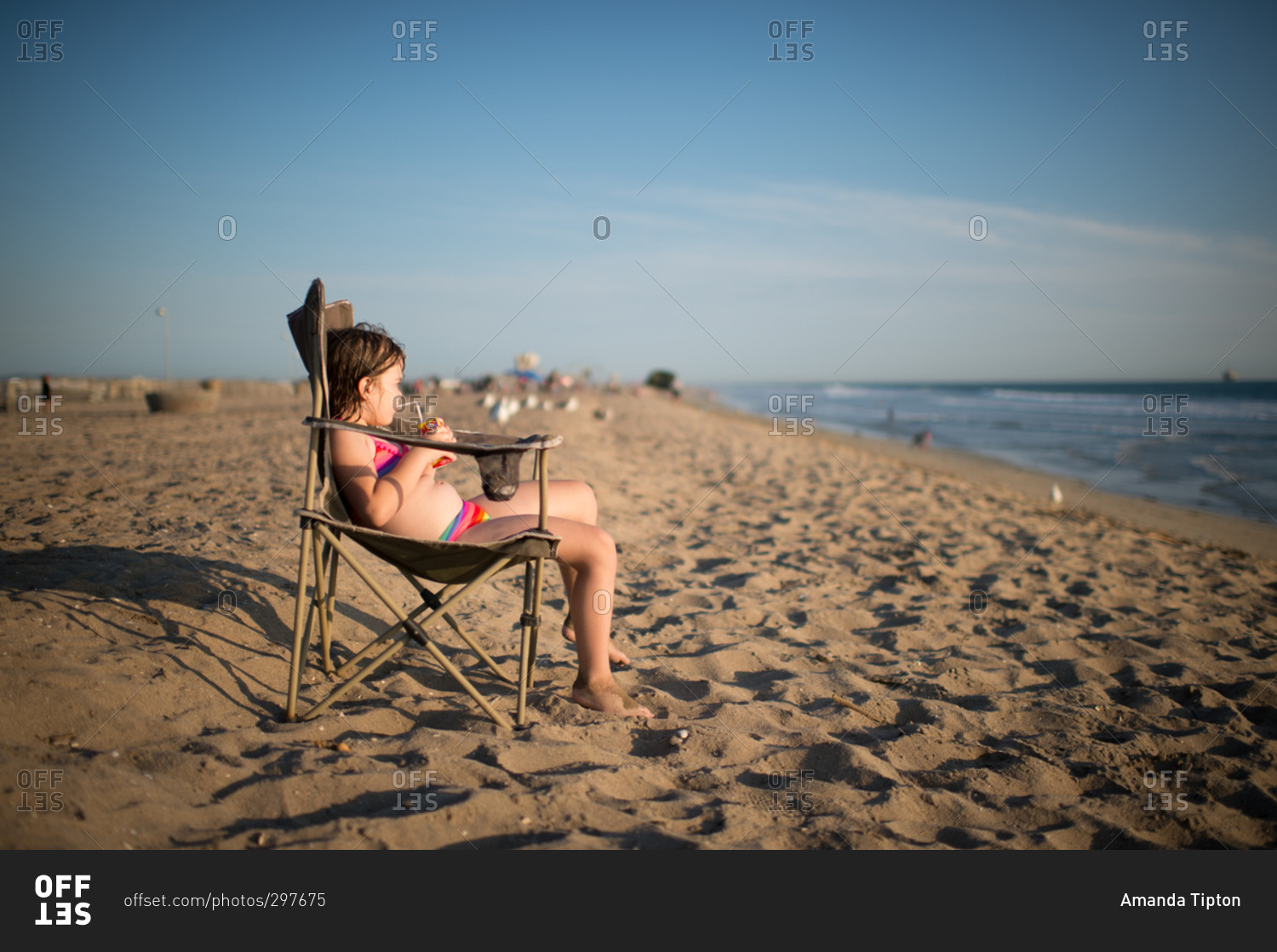 Young girl drinking juice box from a beach chair