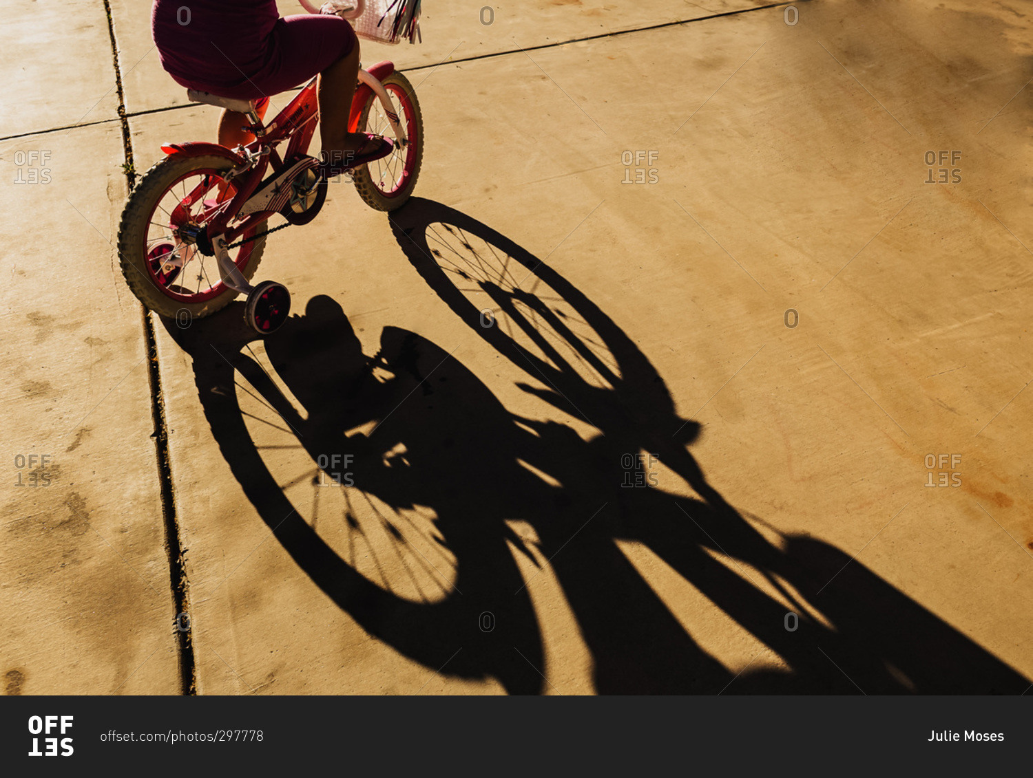 Shadow of young girl riding a bicycle with training wheels