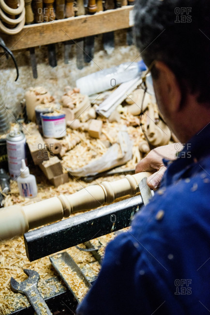 Man carving wood spindle in workshop