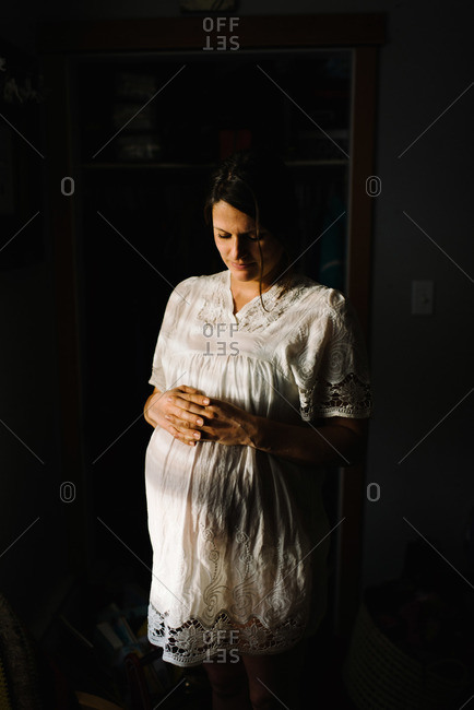 Pregnant woman holding stomach in sunlight