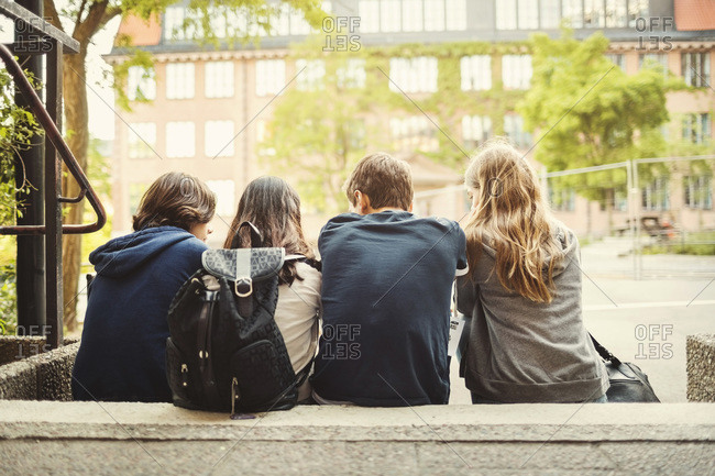 Rear view of teenagers sitting on steps outdoors