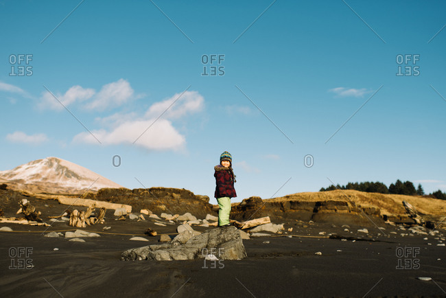 Happy young girl standing on beach rock in winter