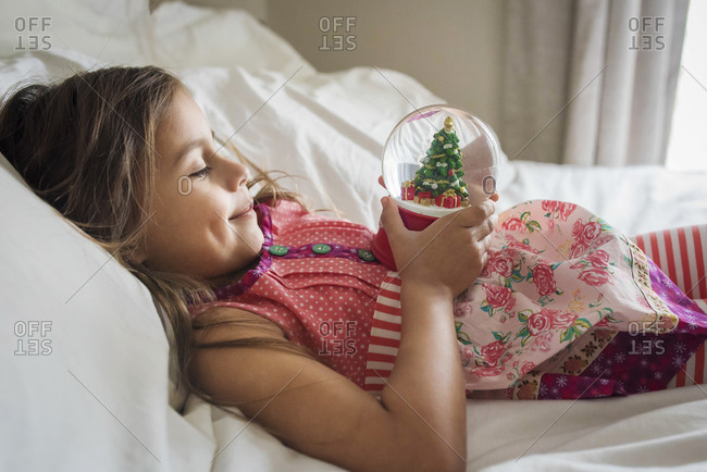 Little girl looking at a snow globe with a Christmas tree inside