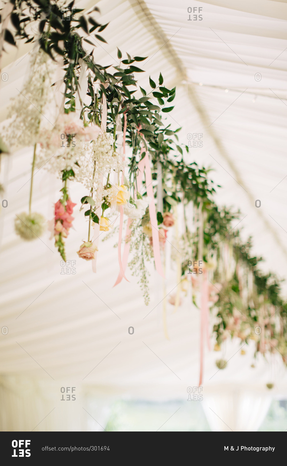 Garland of fresh flowers decorating tent for wedding reception
