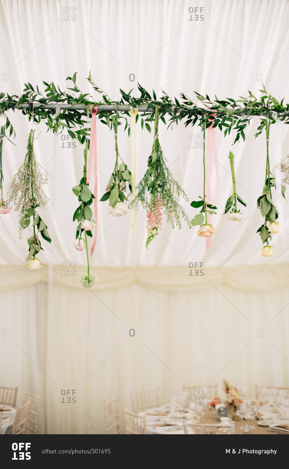 Garland of fresh flowers handing from tent pole for wedding reception