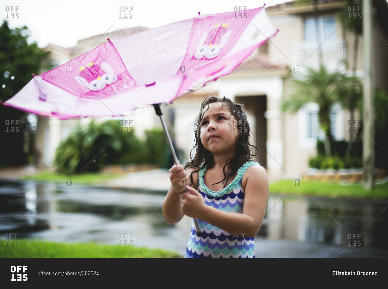 Young girl playing in a rain with an umbrella