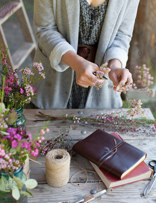 Woman trimming wild flowers on a rustic table