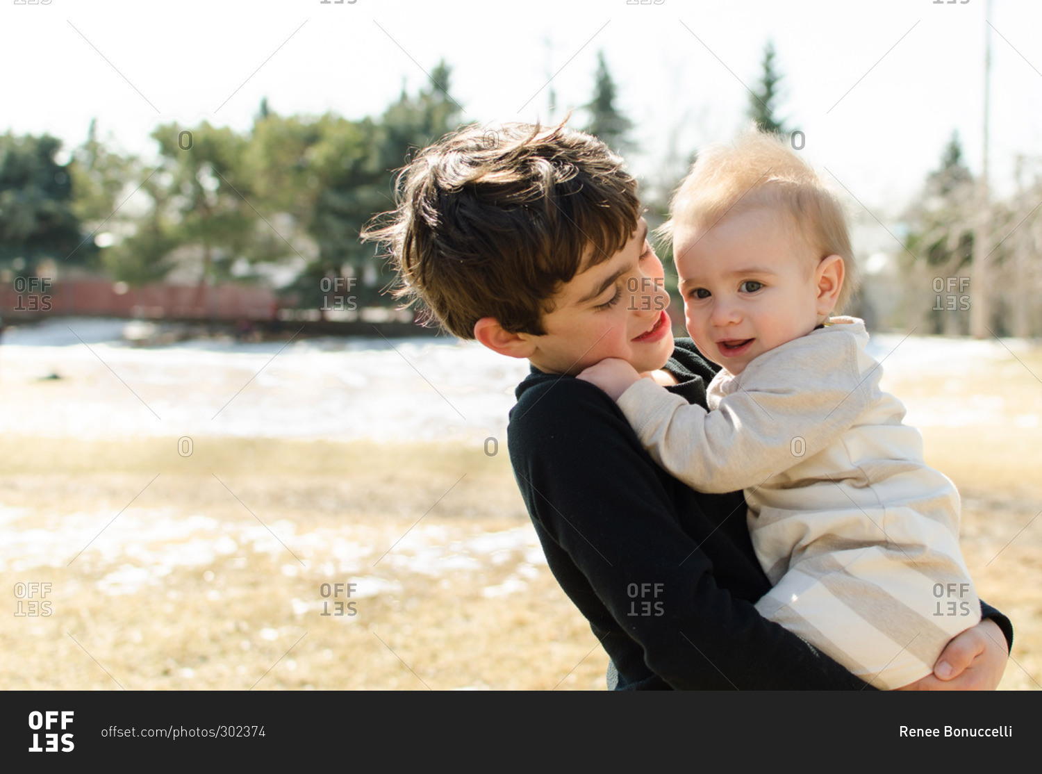 Young boy holding his baby brother stock photo OFFSET