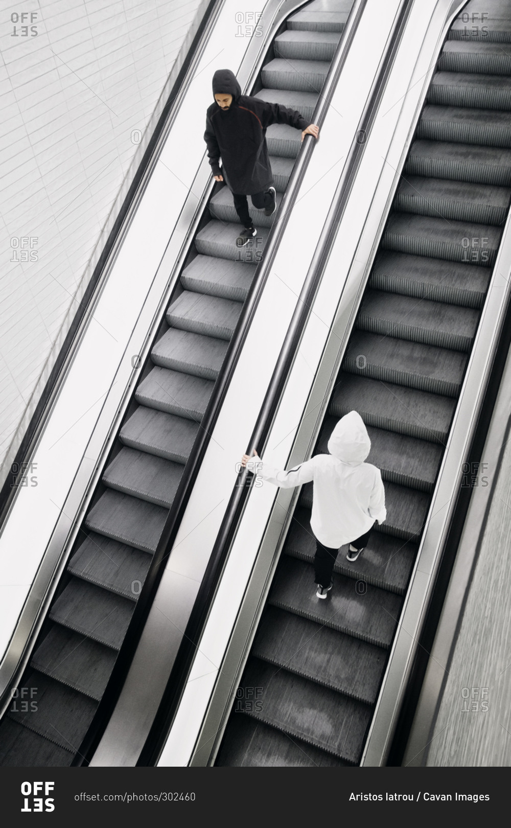 Two people going up and down an escalator