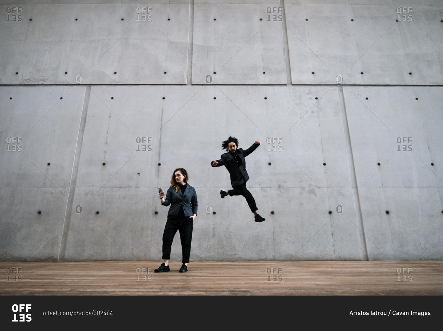 Man doing parkour behind a woman on a smartphone